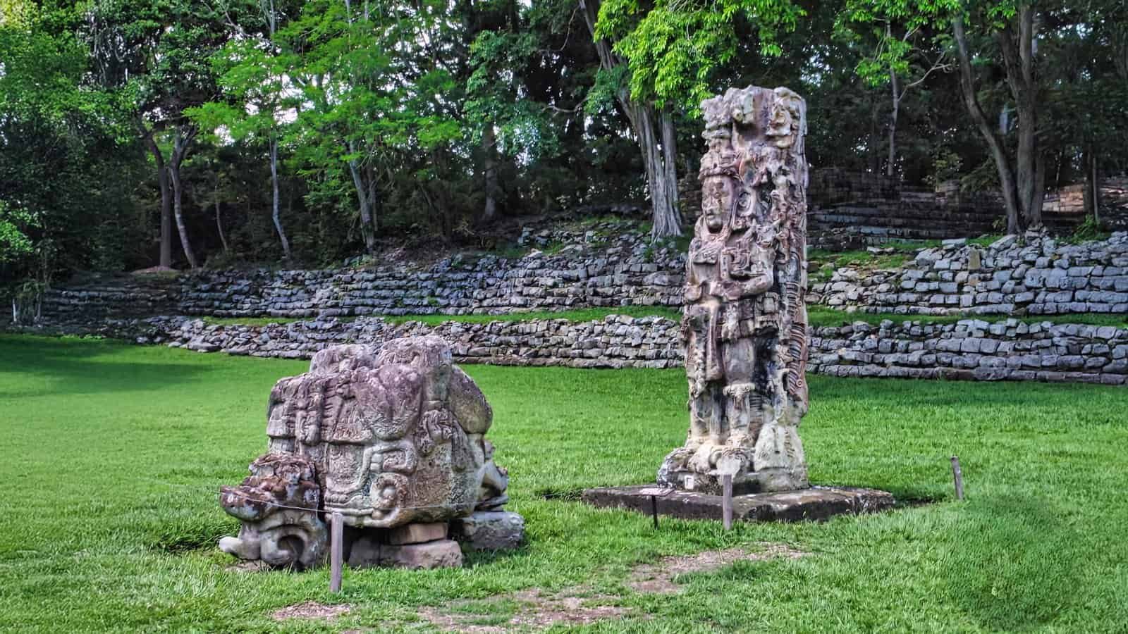 Ancient Mayan stone sculptures at Copan Archaeological Site just 5 minutes from Ancestral Copán Hotel in Honduras, surrounded by lush greenery and archaeological ruins.