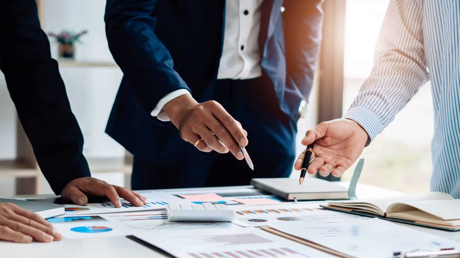 Where Deals Get Done Close-up of business professionals reviewing charts and documents during strategic planning session