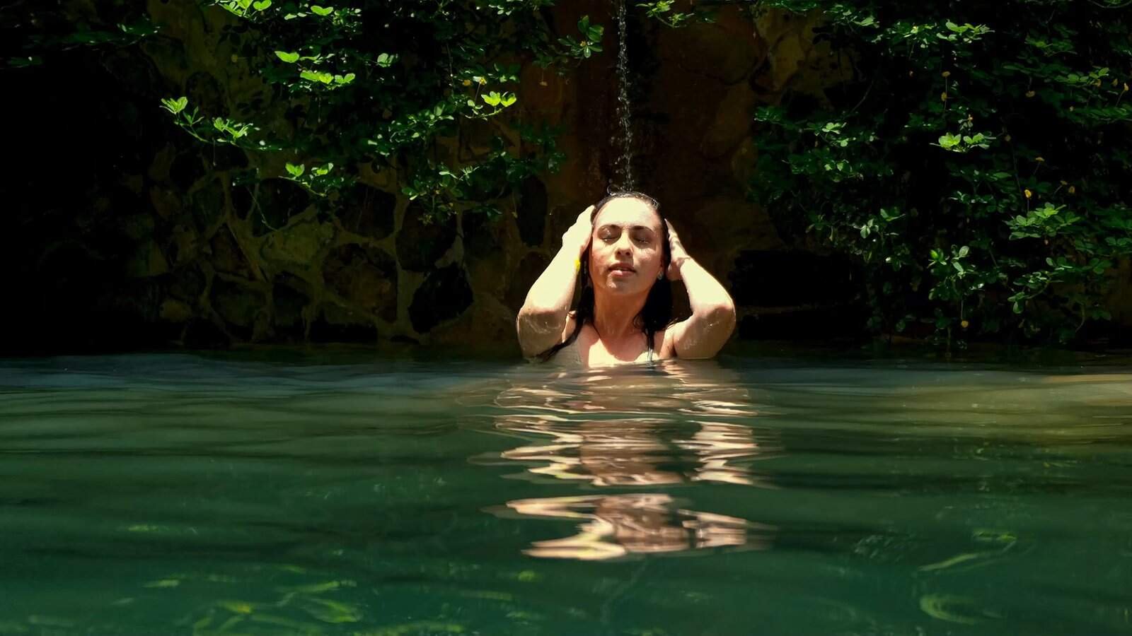 Woman relaxing peacefully in natural thermal pool surrounded by lush jungle vegetation at Luna Jaguar Hot Springs and Spa